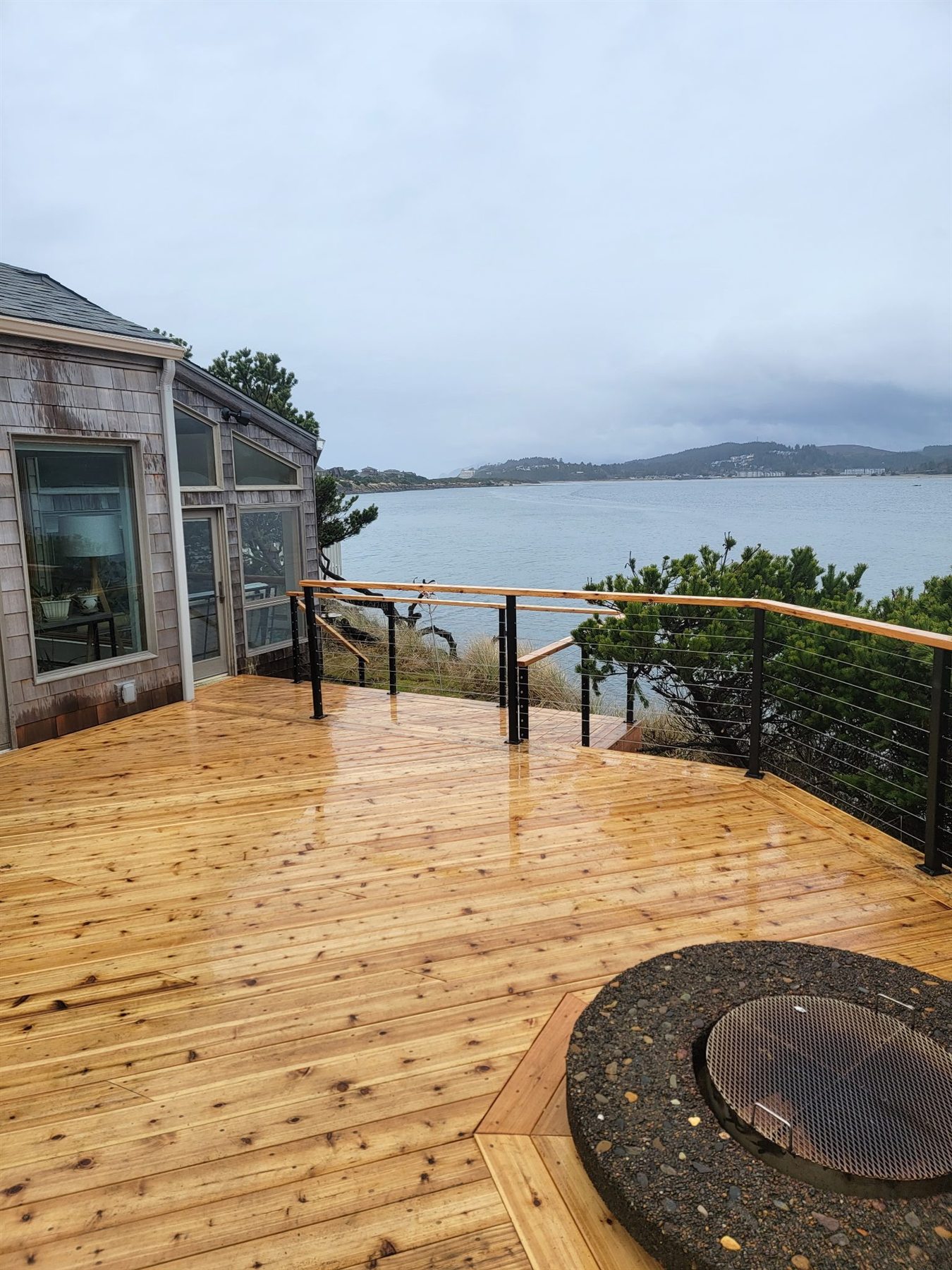 Wood deck with railing, water view, and an inlaid fire pit